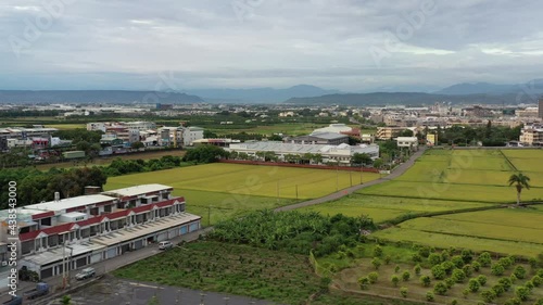 Sliding View Aerial Drone Footage of Urban Agriculture with Grid Farm Land and Rice Paddy Field and Beautiful Blue Sky and Mountains at the background at Doliu City Taiwan. photo