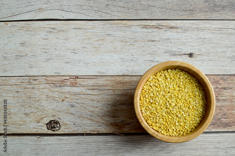 Top Views of Hulled-split Mung Bean in a wooden bowl isolated on the wooden background, Full depth of field. Top Views of Hulled-split Mung Bean in a wooden bowl isolated on the wooden background, Full depth of field.