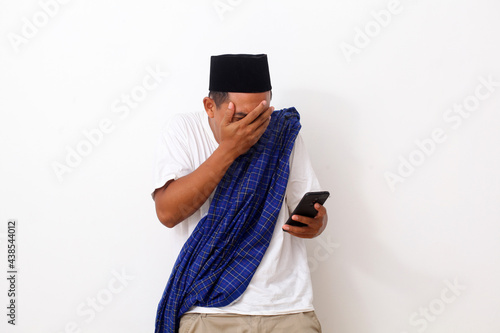 Shocked asian man while looking at his cellular phone. Isolated on white background