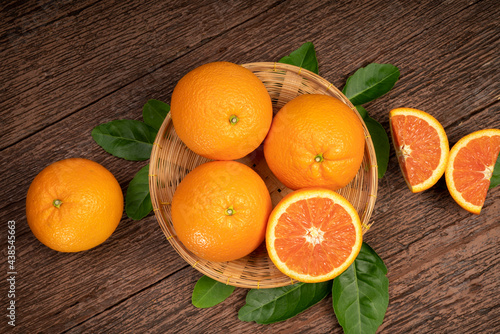 Foto Fresh Oranges with Oranges slices on wooden Basket, Grapefruit or Cara Cara orange with leaves in Wooden background