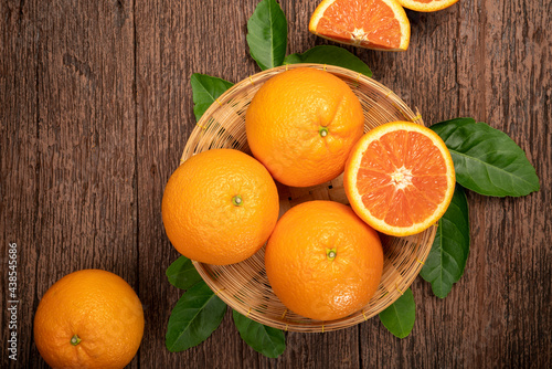 Foto Fresh Oranges with Oranges slices on wooden Basket, Grapefruit or Cara Cara orange with leaves in Wooden background