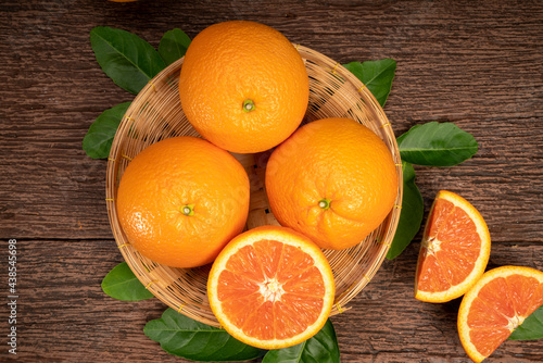 Fresh Oranges with Oranges slices on wooden Basket, Grapefruit or Cara Cara orange with leaves in Wooden background.