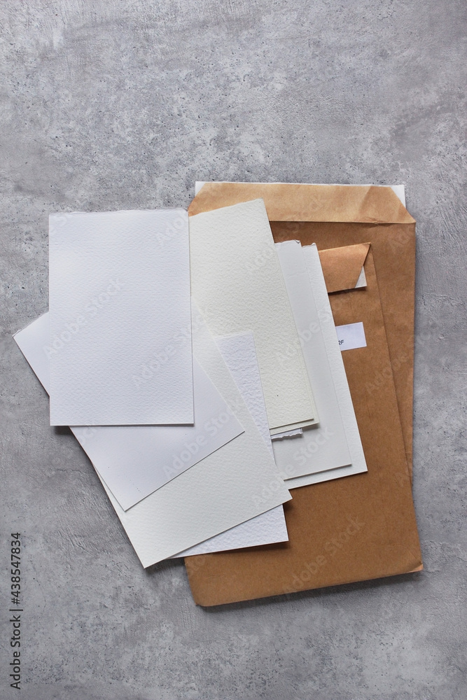 White sheets of paper, craft envelopes on a concrete background. Place for text, illustrations. White sheets of paper, craft envelopes on a concrete background. Place for text, illustrations.
