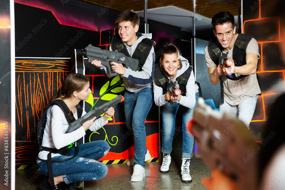 Group of young people with laser pistols having fun on dark labyrinth