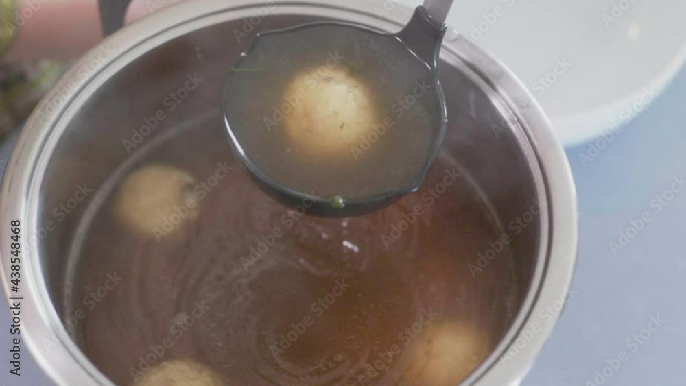 Austrian traditional Semolina dumpling soup fond bullion in a big bowl with a dipper taking soup and a dumpling. Slow motion close up shot camera backwards dolly movement 4K. Austrian traditional Semolina dumpling soup fond bullion in a big bowl with a dipper taking soup and a dumpling. Slow motion close up shot camera backwards dolly movement 4K.