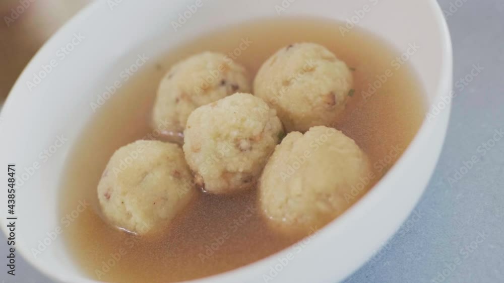Austrian traditional Semolina dumpling soup fond bullion in a white bowl steaming. Slow motion close up shot camera tilting dolly movement 4K. Austrian traditional Semolina dumpling soup fond bullion in a white bowl steaming. Slow motion close up shot camera tilting dolly movement 4K.