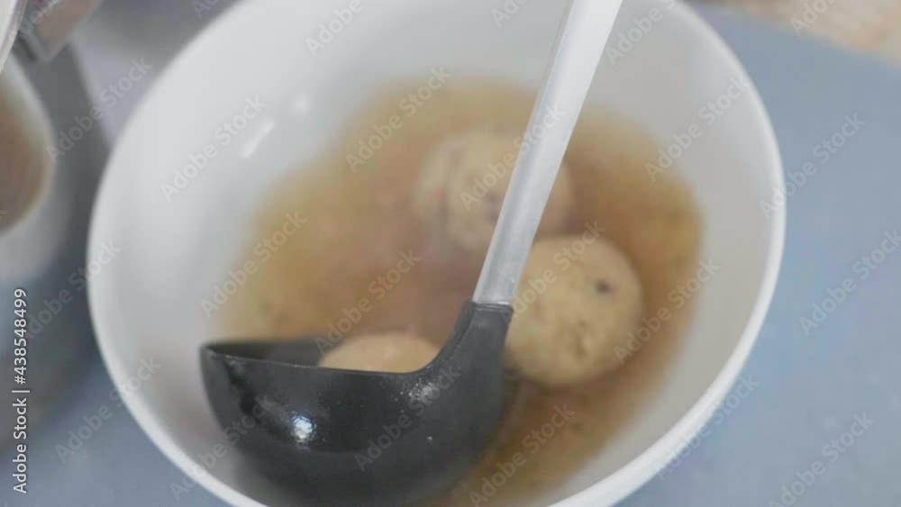 Close up of Semolina dumpling soup being poured from a big scoop into a white bowl. Slow motion shot with smooth dolly camera movement, Shallow depth of Field in 4K. Close up of Semolina dumpling soup being poured from a big scoop into a white bowl. Slow motion shot with smooth dolly camera movement, Shallow depth of Field in 4K.