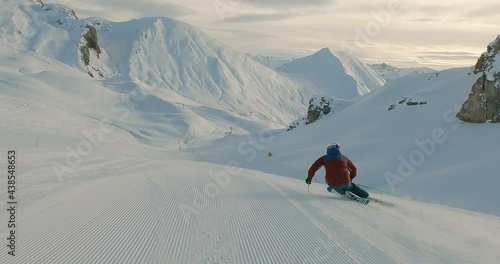 Panorama skiing on a fresh groomed ski slope with the best mountain landscape. Skiing fresh snow in amazing sunrise light on a cold winter day. Downhill skiing 4K follow camera filming.