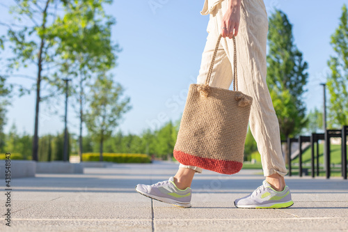 Brown knitted handmade bag in woman hand  in summer park. Eco-friendly shopping. Zero waste lifestyle. DIY jute bag