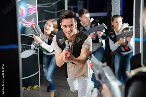 Excited guy laser tag player in bright beams. High quality photo