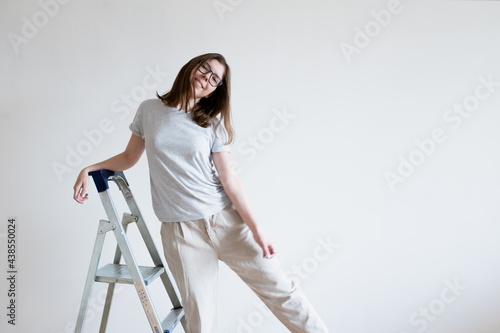 Joyful smiling girl on a stepladder. Repair ladder.