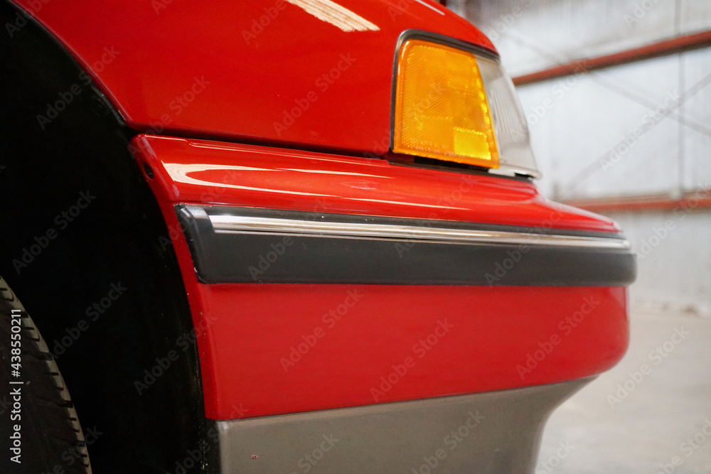 Fototapeta premium red car detail front bumper and turn signal headlight of a red car close up