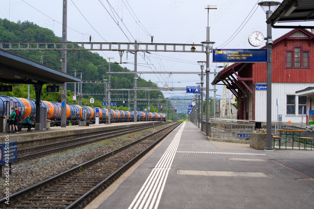 Empty platform at railway station Eglisau, canton Zurich, at summertime with cargo train. Photo taken June 9th, 2021, Eglisau, Switzerland.