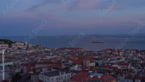 Wallpaper Mural Aerial view of evening city rooftops. Drone flying over red roofs after sunset. Large water surface of Tegus river in background. Lisbon, capital of Portugal. Torontodigital.ca