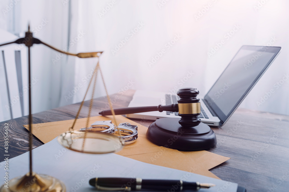 Justice and law concept.Male judge in a courtroom with the gavel, working with, computer and docking keyboard, eyeglasses, on table in morning light Justice and law concept.Male judge in a courtroom with the gavel, working with, computer and docking keyboard, eyeglasses, on table in morning light