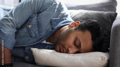 Φωτογραφία Exhausted young Indian man sleeping on couch at home, male feels tired and sleep