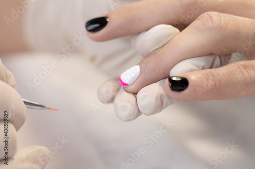 Manicure. Nail coating with colored gel polish by a manicure master in a beauty salon. The concept of professional nail care. Close-up