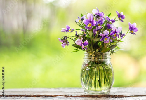 Bouquet of flowers in a vase on a wooden board outdoors on a green background