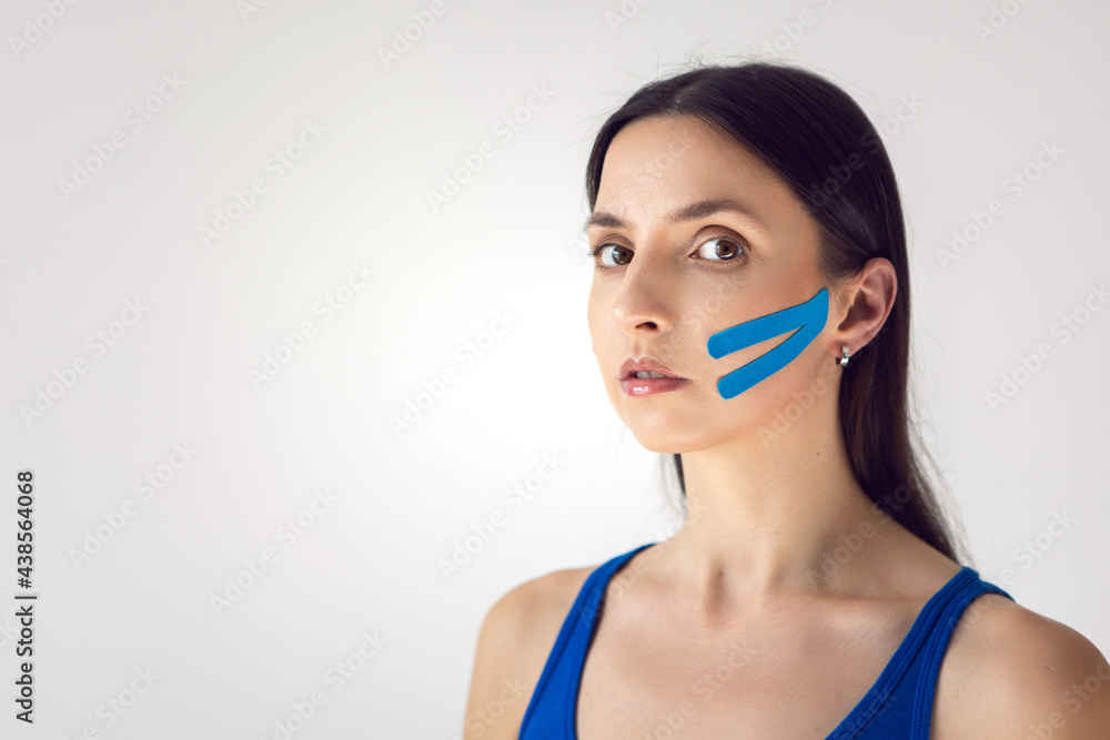 portrait of a young woman with pasted konesiotape for rejuvenation and face tightening portrait of a young woman with pasted konesiotape for rejuvenation and face tightening