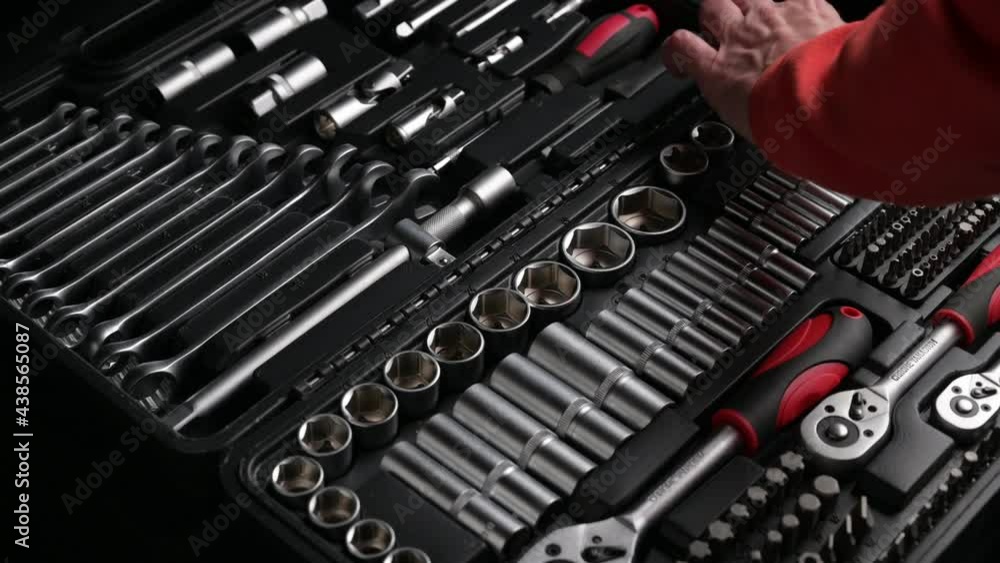 closeup hands of man in red shirt choosing and taking tools from black toolkit connecting and rotating head and chrome spanner ratchet wrench closeup hands of man in red shirt choosing and taking tools from black toolkit connecting and rotating head and chrome spanner ratchet wrench