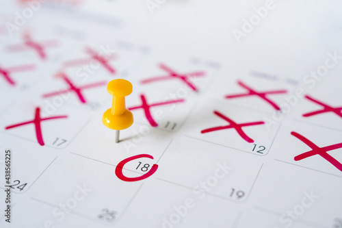 Calendar with yellow pins on May 18. Reminder or deadline concept. Closeup of red pins and red circles.