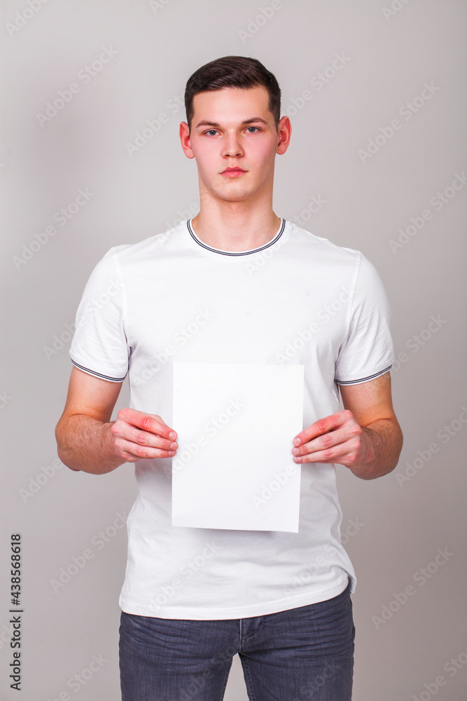 young guy with a blank sheet of paper - place for an inscription young guy with a blank sheet of paper - place for an inscription