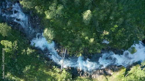 The powerful stream Stikkelvikelva is captured from the air. It is running over the rapids, overcoming the bends, splashing on the rocks, making lots of noise and creating white foam. photo