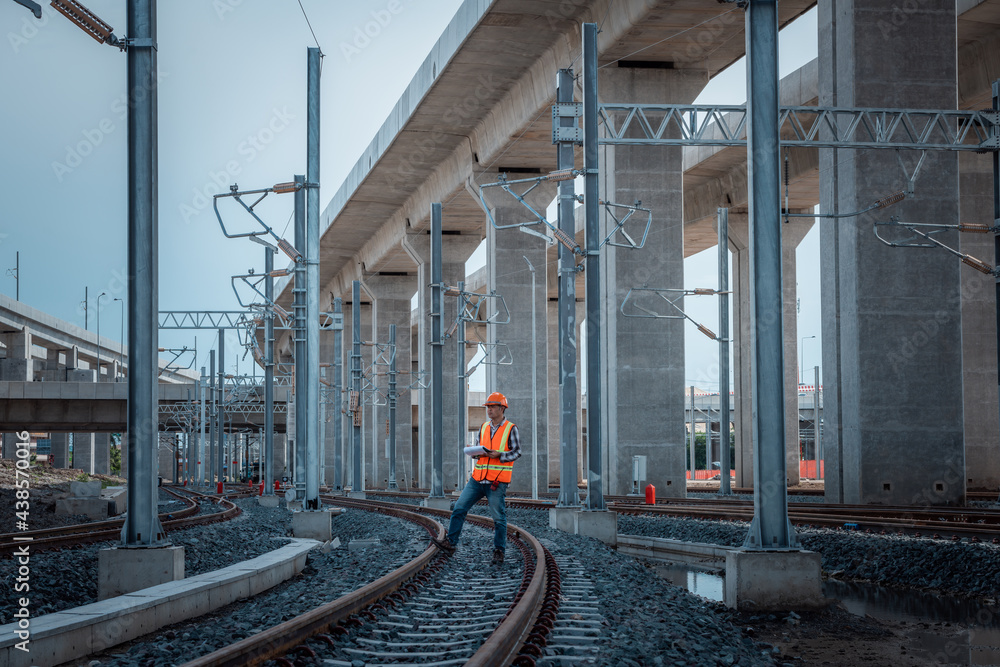Portrait engineer under inspection and checking construction process railway and checking work on railroad station .Engineer wearing safety uniform and safety helmet in work. Portrait engineer under inspection and checking construction process railway and checking work on railroad station .Engineer wearing safety uniform and safety helmet in work.