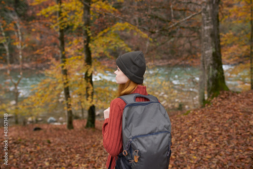 traveler with a backpack and in a gray hat in the autumn forest fallen leaves trees river model