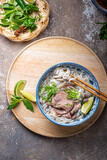 Top view of pho bo vietnamese rice noodle soup with herbs and sauce