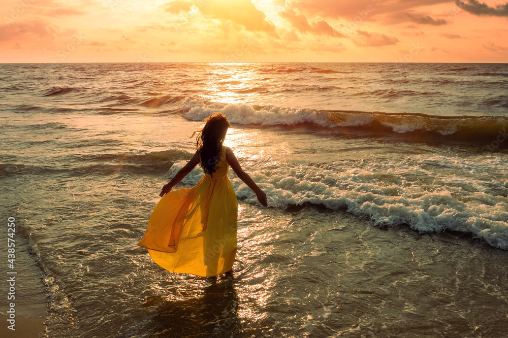 Seascape during golden sunrise with beautiful sky. Woman on the beach.  Young happy woman in a