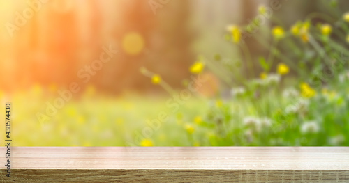 Summer meadow table background. Sunny spring blurred meadow with wooden table background.