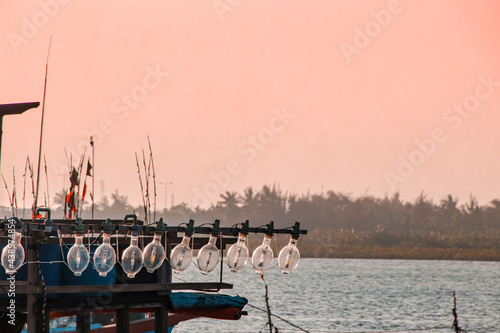 Lights on a fishing boat against the pink sunset sky in Koh Sdach Island in Cambodia photo