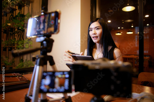 Young asian woman vlogger recording video content for online channel.female looking at camera and talking on video shooting.content creator maker or social influencer concept