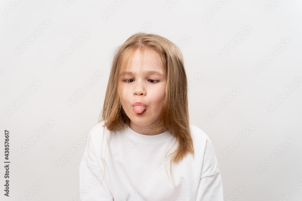 funny girl shows tongue and grimaces on white background funny girl shows tongue and grimaces on white background