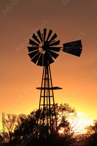 Kansas Windmill silhouette at sunset with a colorful sky north of Hutchinson Kansas USA out in the country.