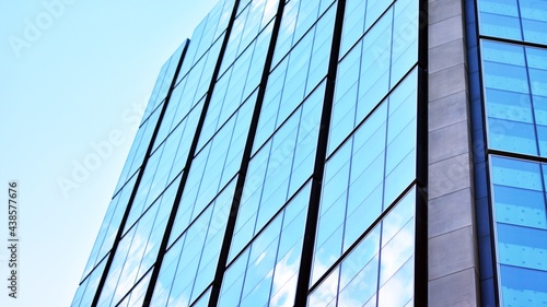 Blue sky and clouds reflected in windows of modern office building. Modern glass facade. 