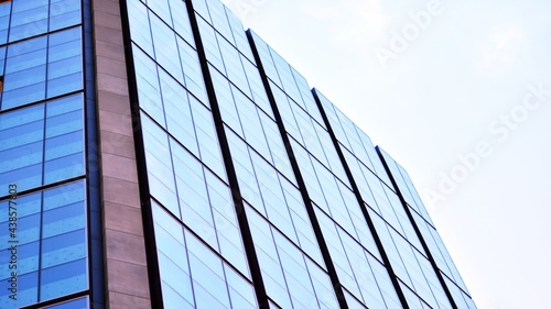 Blue sky and clouds reflected in windows of modern office building. Modern glass facade. 