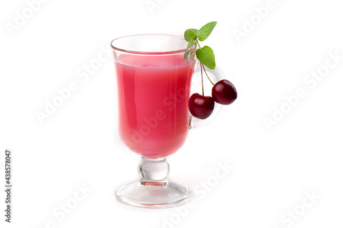 Milk cocktail with cherry in a clear glass and berries on a light background.