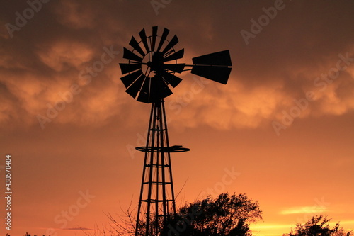 Kansas Windmill silhouette at sunset with a colorful sky north of Hutchinson Kansas USA out in the country.