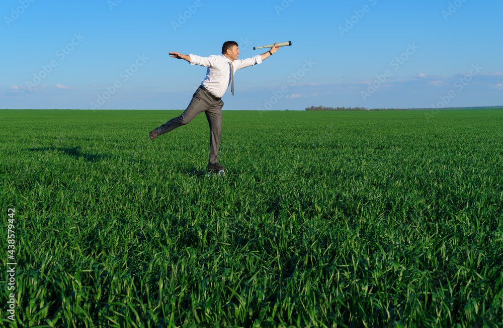 businessman poses with a spyglass in a green field, he looks an idea or something, business concept, green grass and blue sky as background businessman poses with a spyglass in a green field, he looks an idea or something, business concept, green grass and blue sky as background