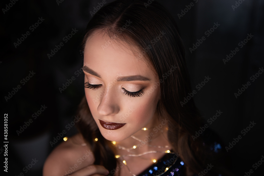 Close-up portrait of beautiful girl with an evening festive, professional make-up, bright, shiny garland around neck. Dark metallic background. Grunge texture of loft interior. Clean skin healthy face Close-up portrait of beautiful girl with an evening festive, professional make-up, bright, shiny garland around neck. Dark metallic background. Grunge texture of loft interior. Clean skin healthy face