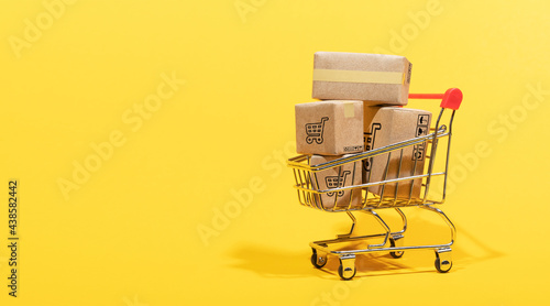 shopping online, paper boxes parcel in a trolley isolated on yellow background. service home delivery.
