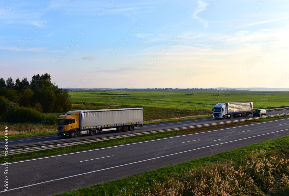 Truck with semi-trailer driving along highway on the sunset background. Goods delivery by roads. Services and Transport logistics. Soft focus.