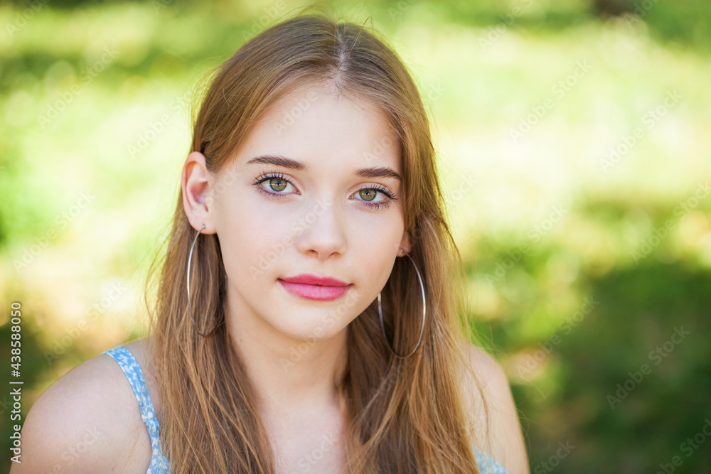 Portrait of a teenage girl on the background of a summer park