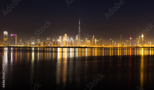 Canvas Print Night view of Dubai city skyline with reflections on the water.