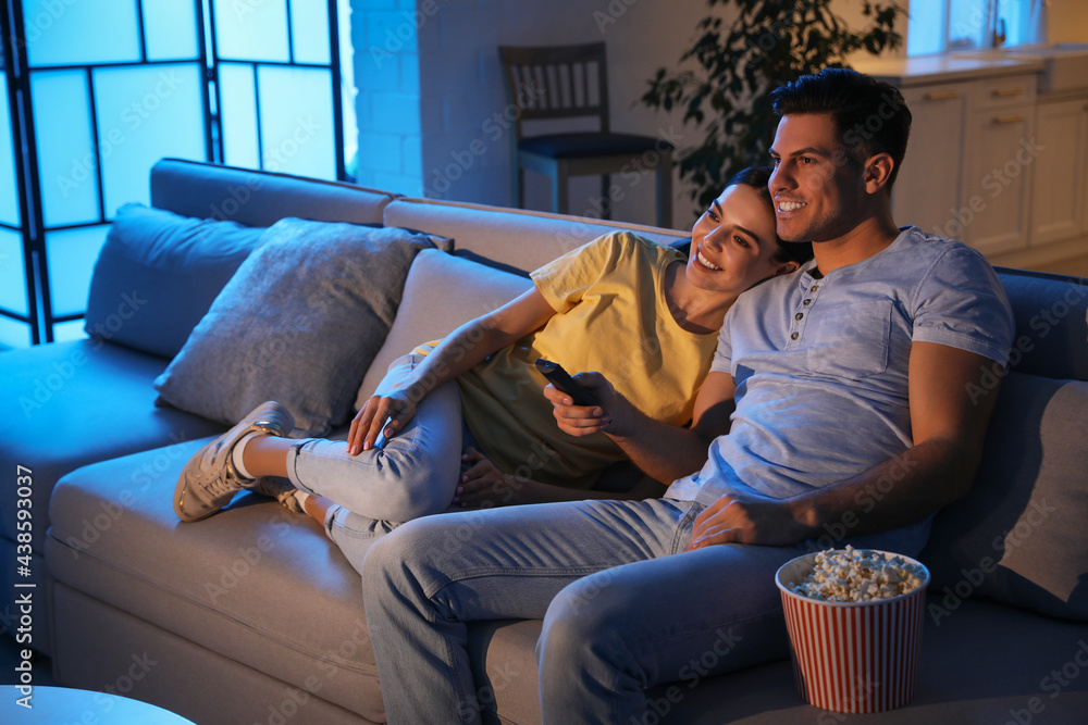 Couple watching movie with popcorn on sofa at night Stock Photo