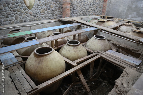 Old ceramics wine jars called kvevri at the wine factory in Georgia. Traditional ceramic pottery barrel for wine. © Maria Kasimova