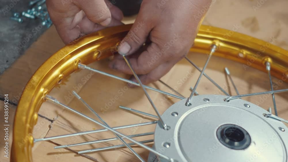 Technician man working motorcycle wheel has spokes weave up on mechanic