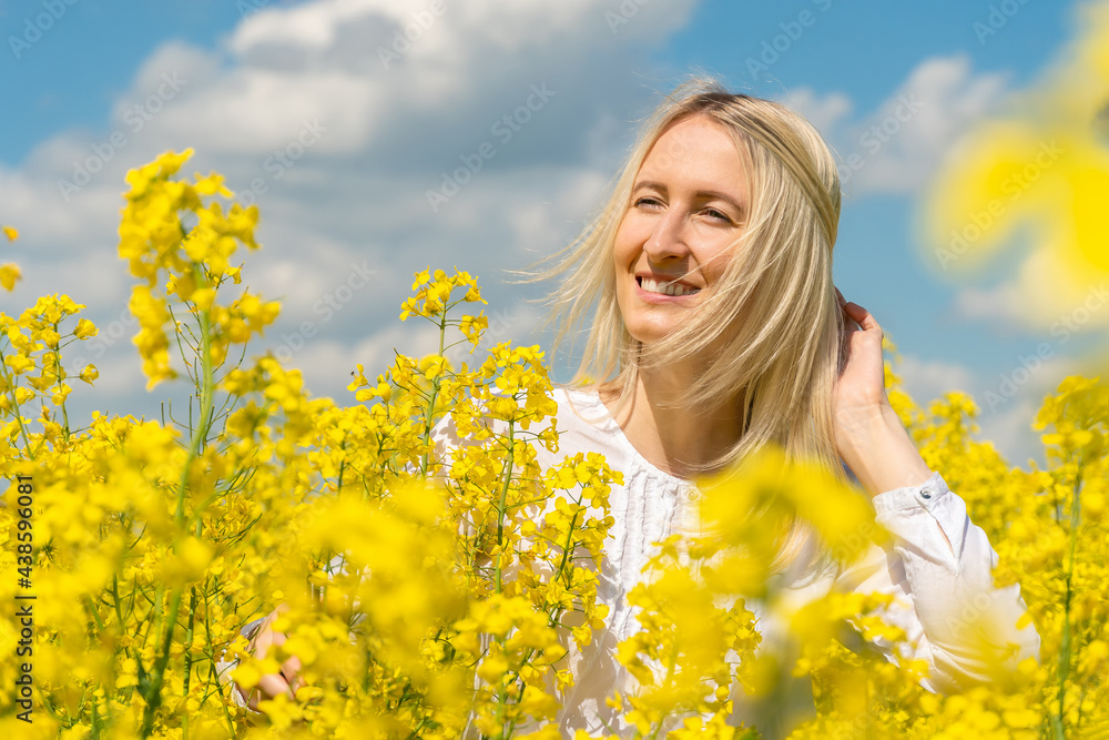 Portrait of a beautiful happy young blonde woman in a white shirt in a rapeseed field on a sunny day Portrait of a beautiful happy young blonde woman in a white shirt in a rapeseed field on a sunny day